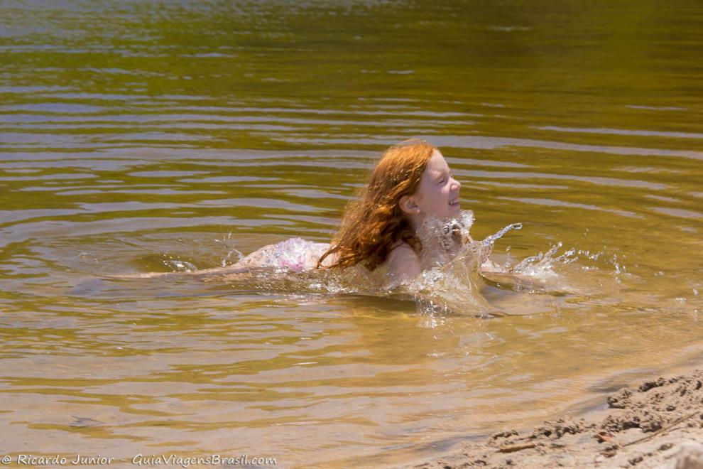 Imagem de uma menina nadando na piscina natural.